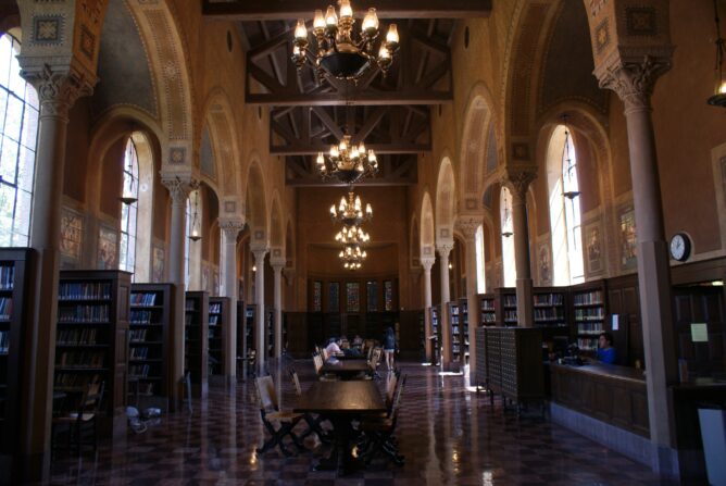 library with high arching ceilings, chandeliers, and alcoves full of books