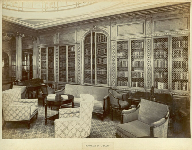 sepia toned photo of reading room with ornate bookshelves and soft chairs