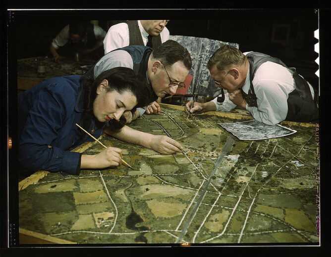 men and women painting on a landscape model